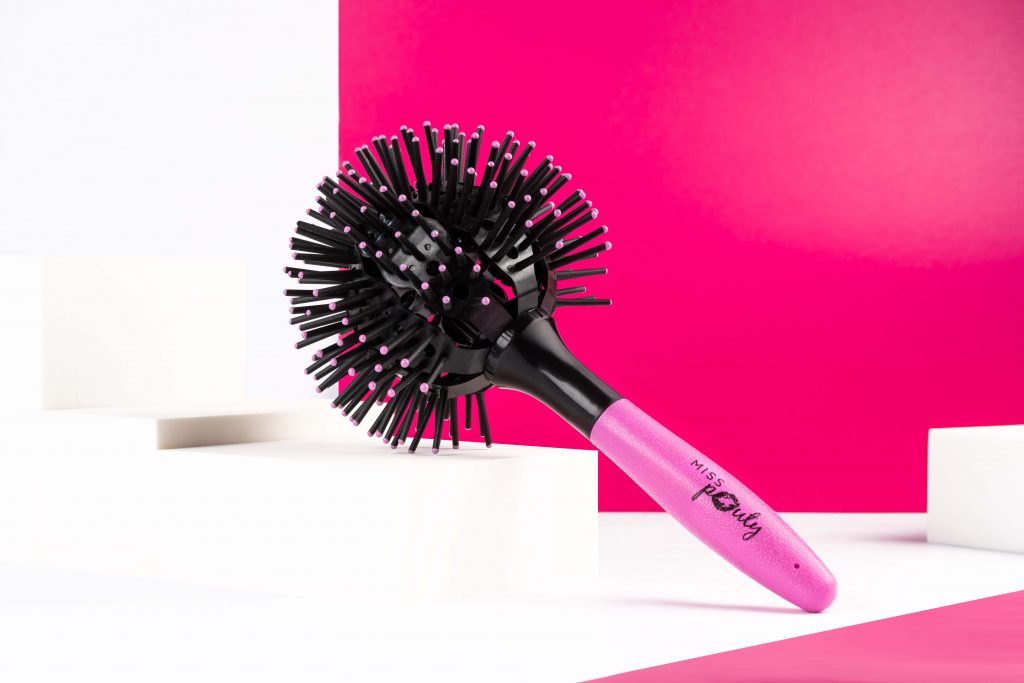 Creative product photography of a retro 360 pink and black hair brush