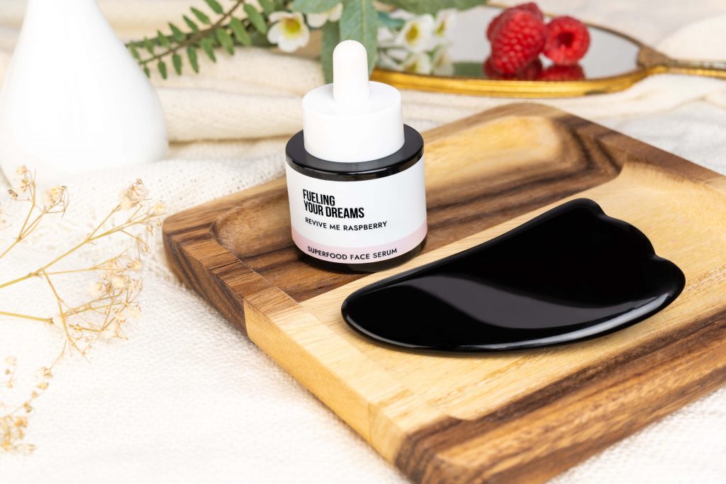 Lifestyle product photo of Raspberry face serum and black gua sha