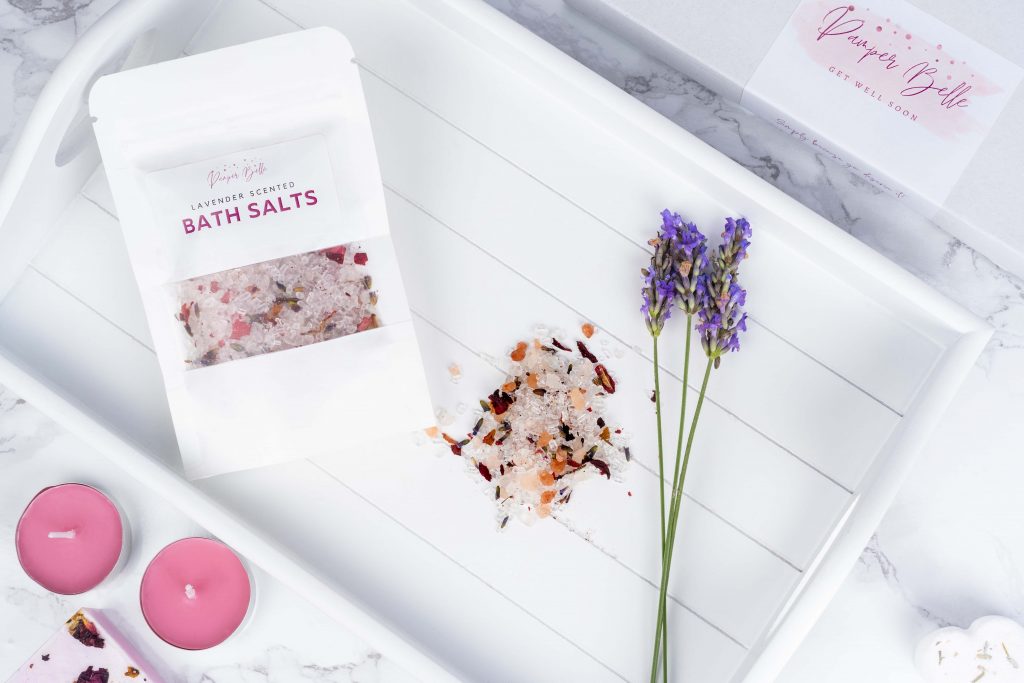 Lifestyle product image of Lavender bath salts in a bathroom. The photo shows the bath salts and fresh lavender in a bathtub tray