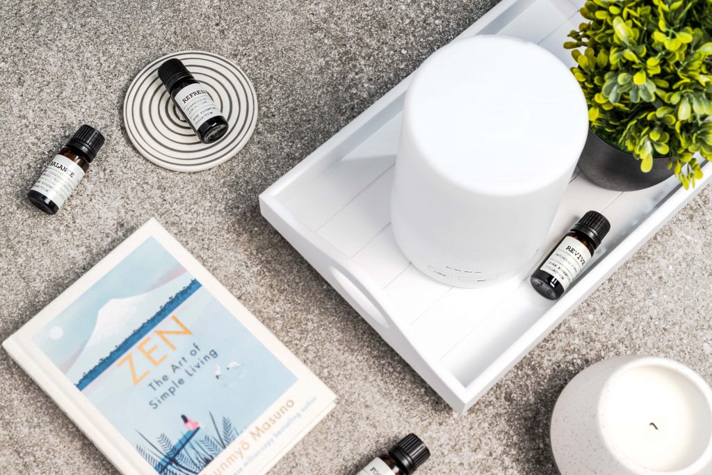 Lifestyle product image of set of 4 essential oils and an oil diffuser